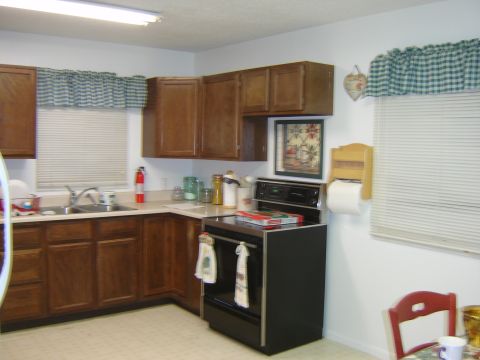 1984 Ford Mustang - A view of a kitchen area wooden cabinets, a black stove, and a sink with blinds on the window.