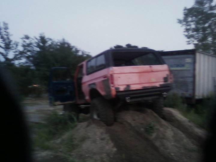 Pink SUV with open driver door on dirt mound, another blue vehicle behind it