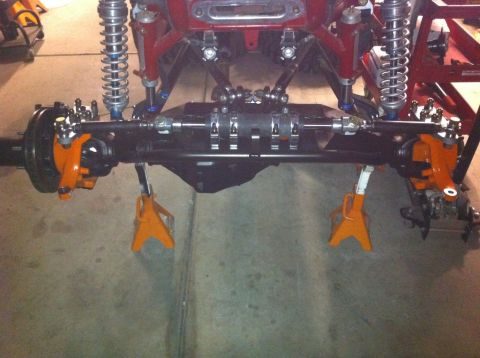 Suzuki Samurai - Front axle assembly with suspension components, resting on jack stands in a garage.