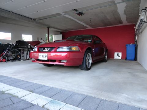 2003 Mercury Marauder - A red Ford Mustang is parked in a garage with bicycles and other items in the background.