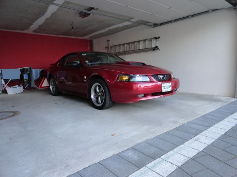 2003 Mercury Marauder - Red Ford Mustang coupe parked in a garage, showing its front 3/4 view with a visible license plate.