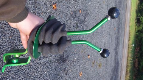 1979 Ford Bronco - A hand holds a pair of green dual stick shift levers with black knobs, likely for a 4x4 vehicle.
