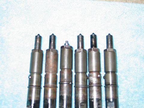 1984 Ford Bronco - Set of six diesel fuel injectors, some with visible rust and wear.