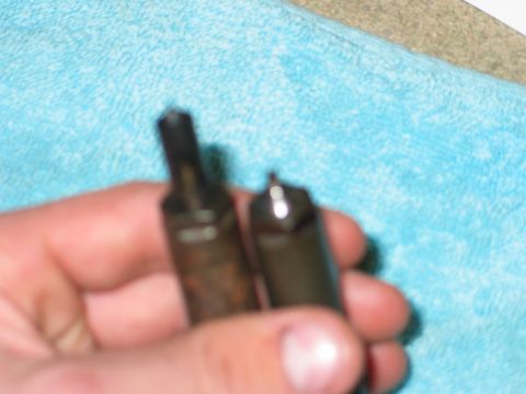 1984 Ford Bronco - Close-up of two fuel injectors being held, one showing more wear than the other.