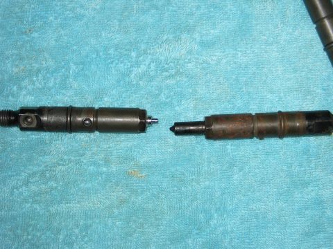 1984 Ford Bronco - Two fuel injectors are shown on a blue towel, one appearing cleaner than the other.