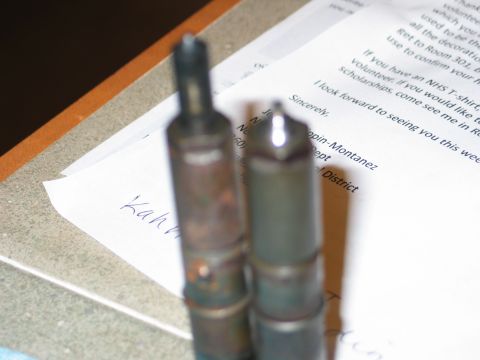 1984 Ford Bronco - Two diesel injectors are placed on top of a document with handwritten and typed text.