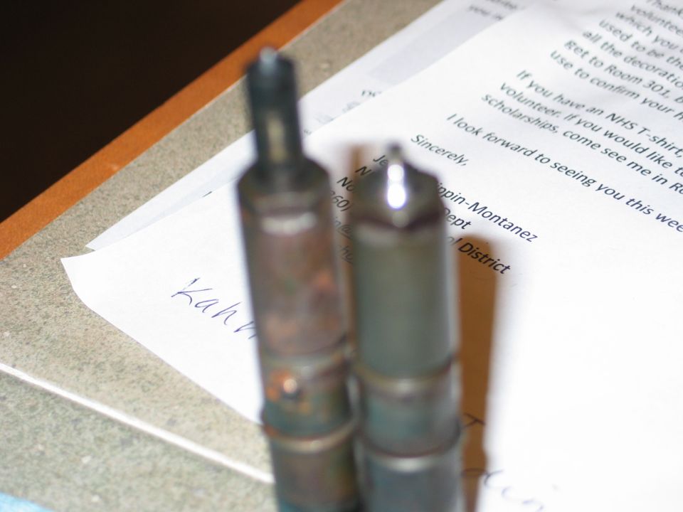 Two diesel injectors on top of a document. One injector is darker and appears older