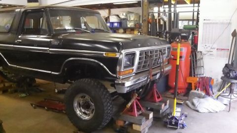 1979 Ford Bronco - This black Ford Bronco is raised on jack stands in a workshop, undergoing maintenance.