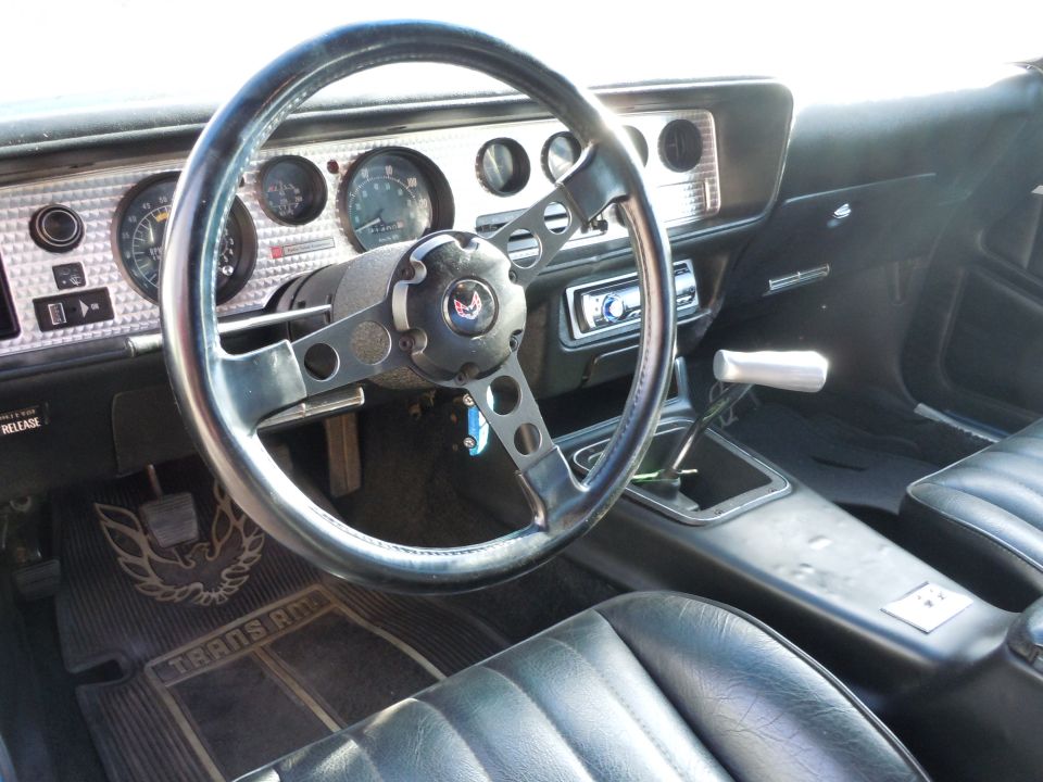Interior shot of a 1976 Pontiac Trans Am showing the steering wheel, dashboard, and seats