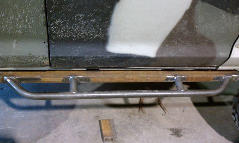 1979 Ford Bronco - Custom rock sliders are being installed on the side of a vehicle.