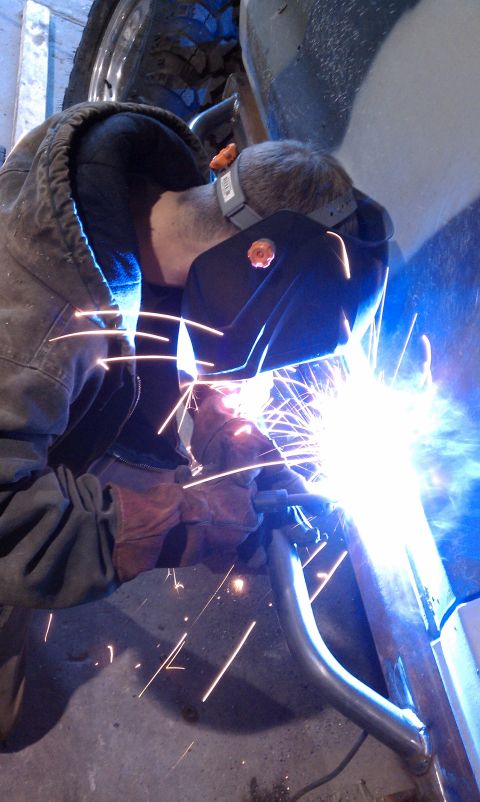 1979 Ford Bronco - A person is welding a metal component, with sparks flying and a tire visible in the background.