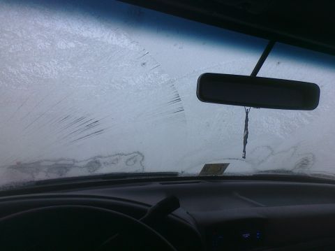 1995 Ford Bronco - The interior of a vehicle is shown, with the windshield covered in frost and ice.