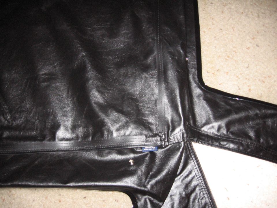 Black vinyl soft top panel with seams, snaps and zipper laid on carpet
