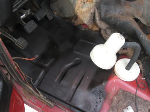 1981 Ford Bronco - The interior floor of a vehicle undergoing repair, showing pedals and wiring.