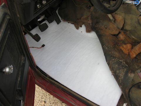 1981 Ford Bronco - The interior of a car shows white insulation laid over the floorboards, with remnants of old carpet.