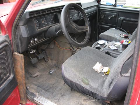 1981 Ford Bronco - The interior of a red truck, likely from the 1980s, is visible from the driver's side perspective.