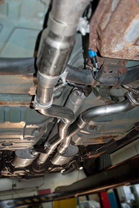 1998 Ford Crown Victoria - The underside of a vehicle displays a custom dual exhaust system with polished pipes and mufflers.