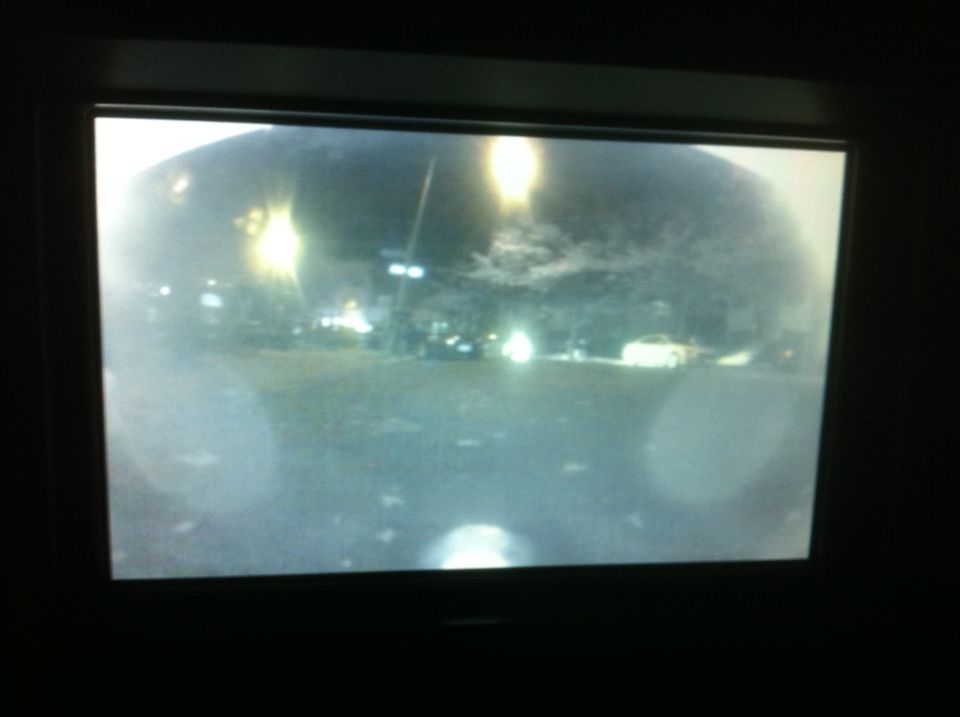 Backup camera view shows a dark parking lot with streetlights and a few cars visible
