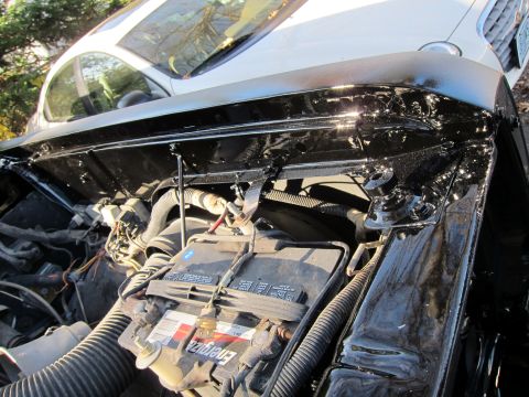 1987 Dodge 1500 - Engine bay detail a black painted finish and a prominent battery.
