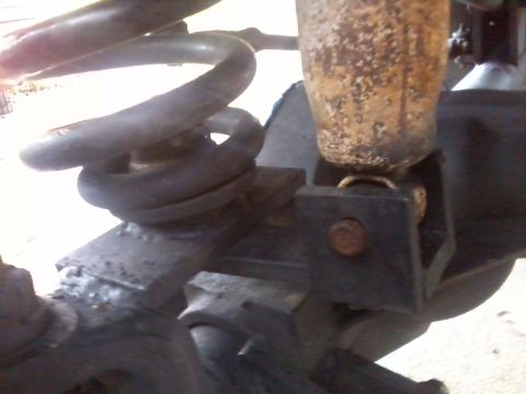1986 Ford Bronco - Detail shot of the suspension system, showing a coil spring and a heavily rusted shock absorber.