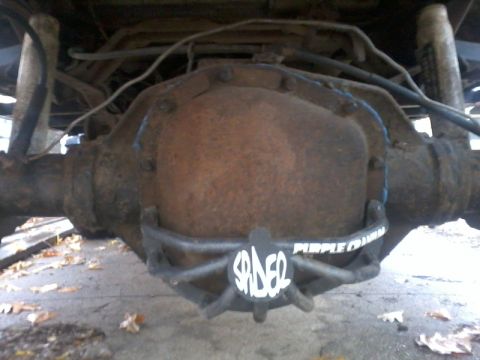 1986 Ford Bronco - Close-up of a heavily rusted differential housing with custom labels, suggesting aftermarket modifications.