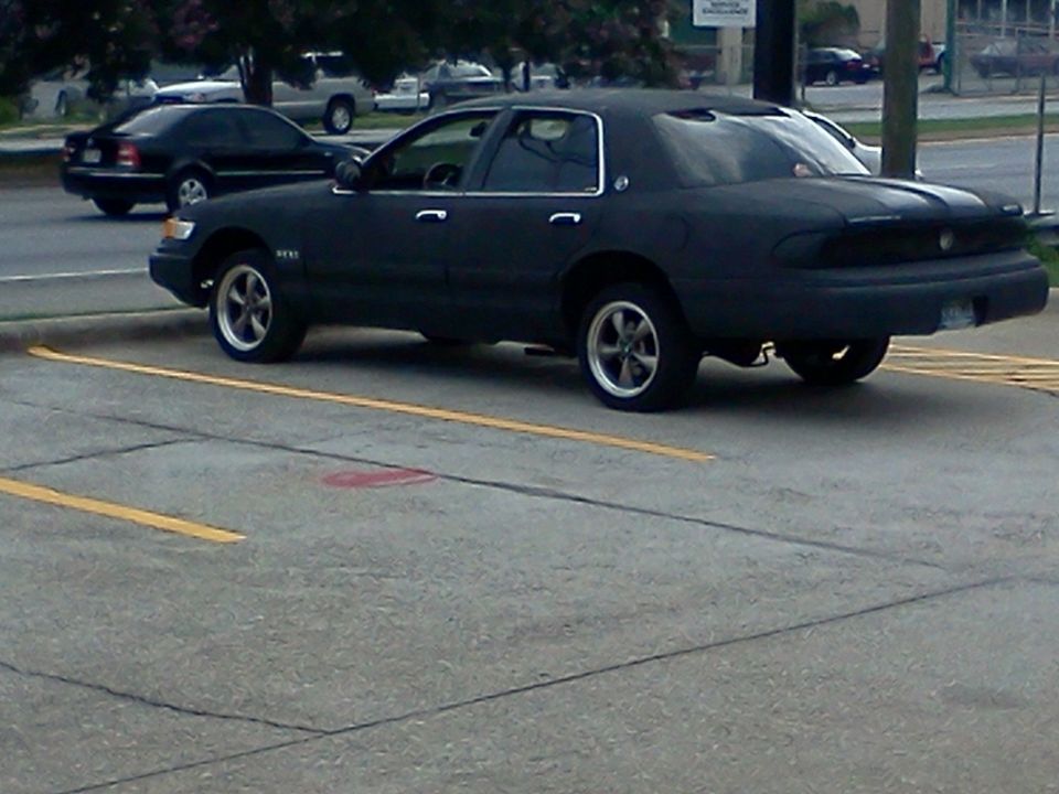dark sedan parked, another black sedan in background