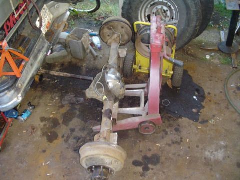1993 Ford Bronco - Rear axle assembly is on a dolly, with a vehicle's side and wheels in the background.