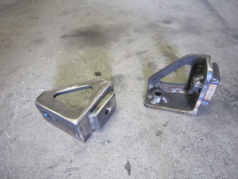 2008 Jeep Wrangler - Two custom-fabricated metal brackets, likely for a winch mount, sit on a concrete floor.