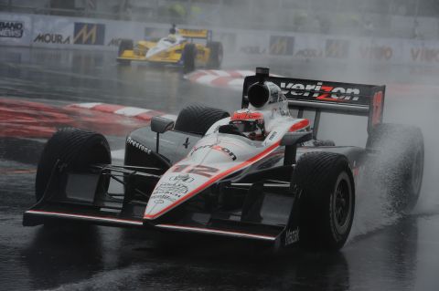 1993 Ford Taurus - An open-wheel race car navigates a wet track, kicking up spray as it competes.