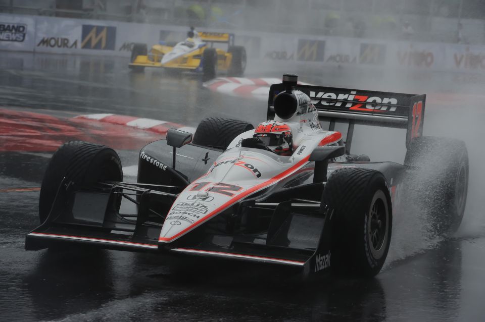 Open-wheel race car with Verizon sponsorship on track in the rain