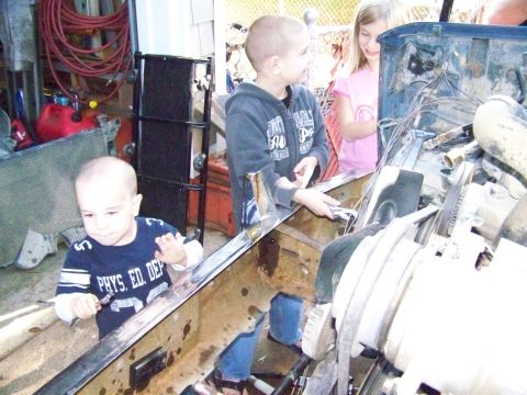 1985 Ford Bronco - Kids explore the engine compartment of a vehicle, possibly during a repair or swap.
