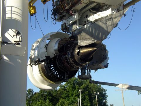 1992 Ford Taurus - A large jet engine is being worked on, suspended from a crane against a clear blue sky.