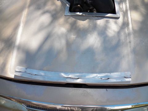 1993 Ford Crown Victoria - Metalwork is being performed on the hood of a vehicle, with engine components visible underneath.