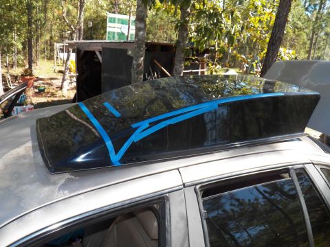 1993 Ford Crown Victoria - A car's roof is prepared for a spoiler installation with blue tape securing the part.