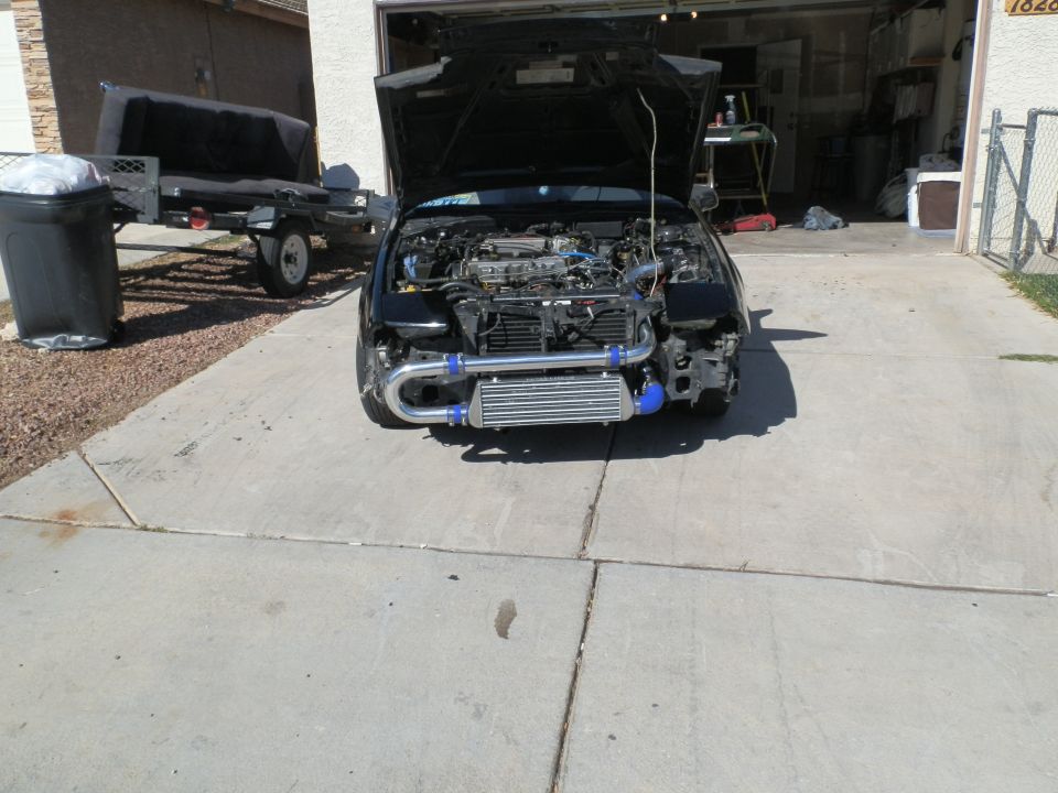 Black car with hood open, showing engine and aftermarket intercooler. Front bumper is removed
