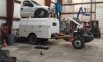1994 Ford Probe - A workshop scene shows a white pickup truck loaded onto a utility trailer, with a piece of machinery in front.