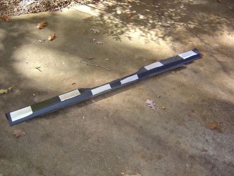1986 Ford Bronco - A detached vehicle bumper section lies on a concrete surface with fallen leaves.