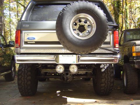 1986 Ford Bronco - The rear of a gray Ford Bronco is shown with a spare tire mounted and a chrome bumper.