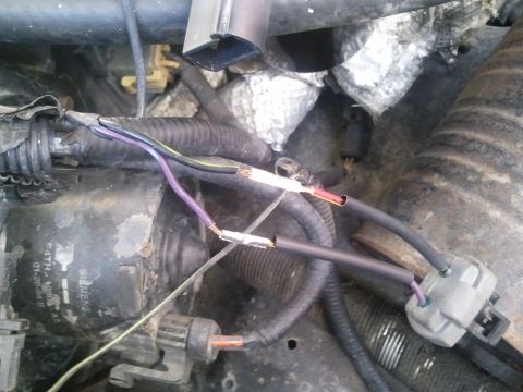 1994 Ford Bronco - Close-up of an engine wiring harness showing exposed wires and connectors, with some text visible on a component.