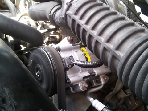 1994 Ford Bronco - Vehicle AC compressor and drive belt shown in detail within the engine compartment.