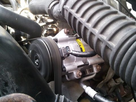 1994 Ford Bronco - The AC compressor and drive belt are visible in this engine bay detail shot.
