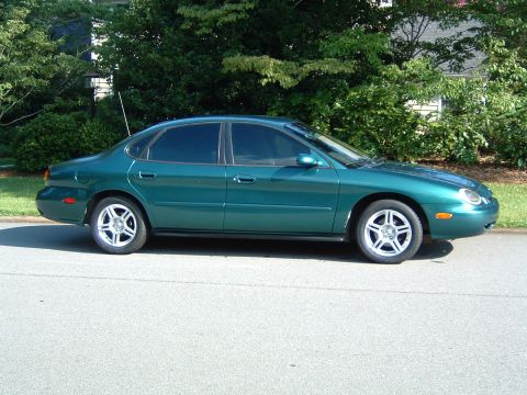 1997 Ford Taurus - Side profile of a green 1997 Ford Taurus sedan parked on a residential street.