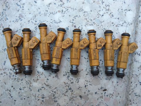 1998 Ford Crown Victoria - A set of eight yellow fuel injectors are shown, with some text visible on their sides.