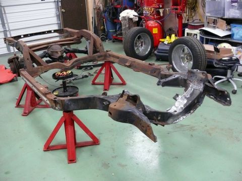 1976 Chevrolet Corvette - A disassembled car frame rests on jack stands in a garage, awaiting restoration.
