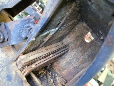 1976 Chevrolet Corvette - Close-up view of heavily rusted metal framing with deteriorated wood components.