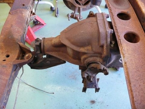 1976 Chevrolet Corvette - Close-up of a rear differential assembly attached to a heavily rusted vehicle frame, with a Supermotors.net watermark visible.
