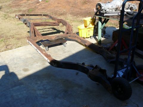 1976 Chevrolet Corvette - This is a rusted car frame on dollies. An engine and yellow bucket are visible in the background.