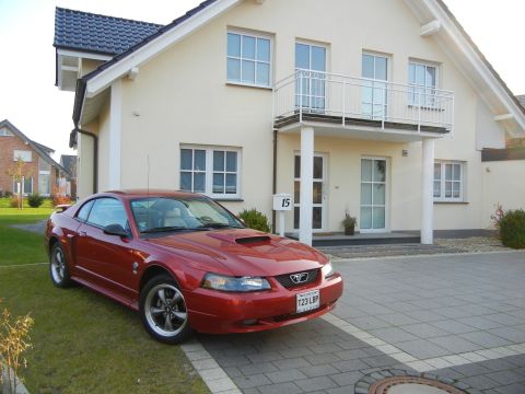 2003 Mercury Marauder - A red Ford Mustang is parked on a driveway in front of a modern house.
