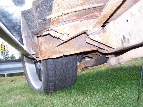 1969 Chevrolet C/K Pickup - The undercarriage of the vehicle displays extensive rust damage, particularly on the frame and rocker panel areas.