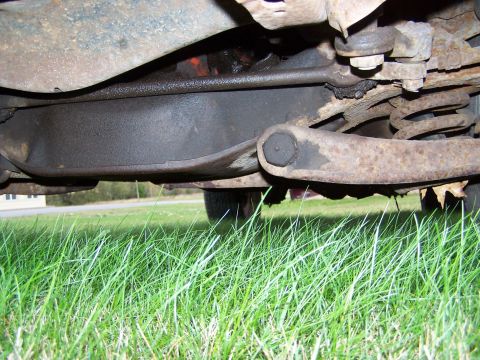 1969 Chevrolet C/K Pickup - Close-up view of the rusty undercarriage of a vehicle, showing suspension parts and the differential.